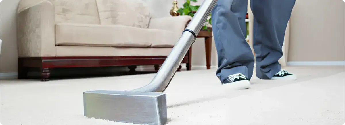 Carpet cleaning technician using a hot-water extraction wand on a light-colored carpet in a living room, Boca Raton, FL.
